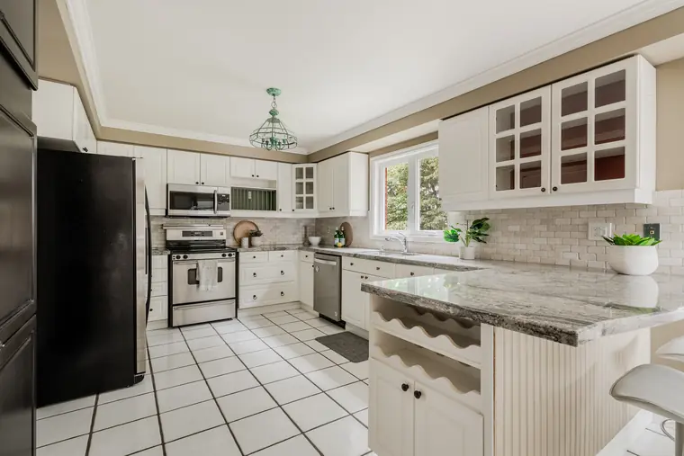 Kitchen with white cabinetry, stone breakfast bar and stainless steel appliances