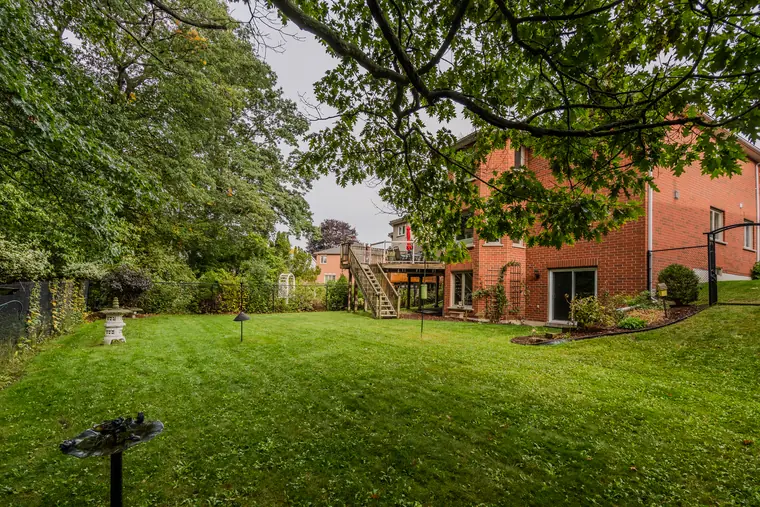 Backyard lawn with the home behind, framed by mature trees